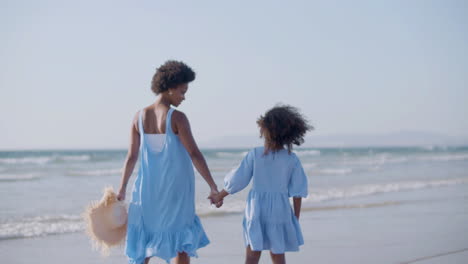 Glückliche-Frau-Und-Tochter,-Die-Am-Strand-Spazieren-Gehen,-Händchen-Halten-Und-Miteinander-Reden