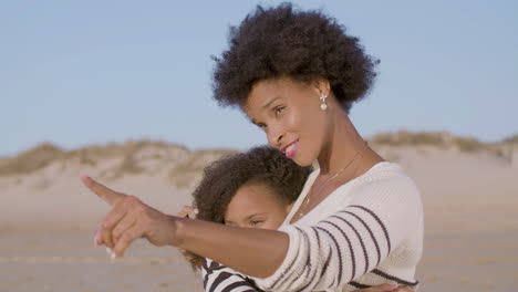 Happy-Mother-Hugging-And-Talking-With-Her-Cute-Daughter-At-The-Beach