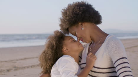 Loving-Mother-And-Daughter-Hugging-And-Touching-Their-Noses-On-The-Beach