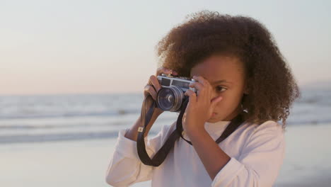 Hübsches-Mädchen-Mit-Dickem-Lockigem-Haar,-Das-Mit-Einer-Digitalkamera-Am-Strand-Fotografiert
