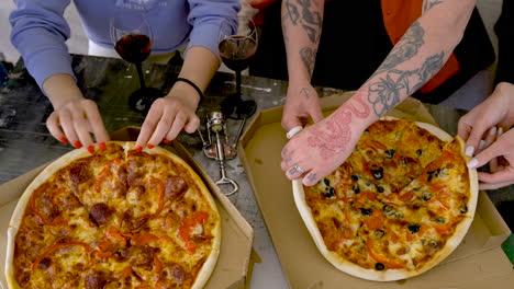 Close-Up-Of-Unrecognizable-Friends-Sharing-Pizza-At-Home
