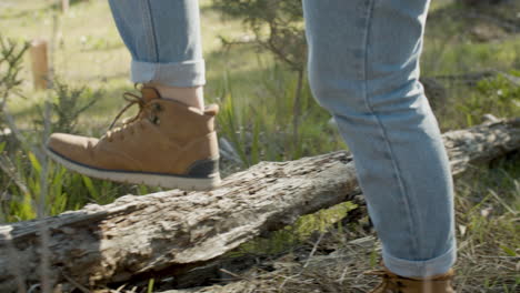 Close-Up-Shot-Of-Two-Unrecognizable-Hikers-Walking-In-The-Forest-And-Stepping-On-A-Wooden-Log-On-A-Sunny-Day