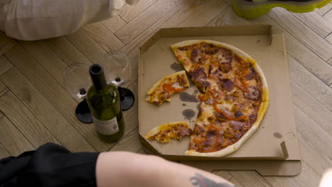 Top-View-Of-Pizza,-Wine-Bottle-And-Glasses-On-A-Wooden-Floor