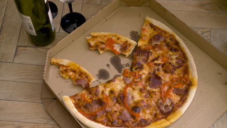Vista-Superior-De-Una-Pizza-En-Un-Cartón-En-Un-Piso-De-Madera