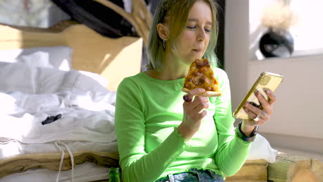 Junge-Blonde-Frau,-Die-Handy-Benutzt-Und-Pizza-Isst,-Während-Sie-Zu-Hause-Auf-Dem-Boden-Im-Schlafzimmer-Sitzt-1