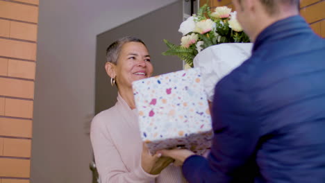 Courier-Delivering-Flowers-And-Gift-Box-To-A-Surprised-Woman-At-Her-Home