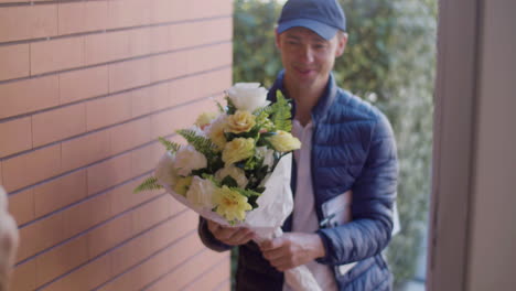 Woman-Opening-Door,-Receiving-Bouquet-Of-Flowers-From-Courier-And-Signing-The-Clipboard