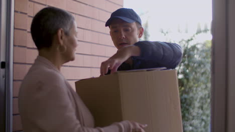 Back-View-Of-Short-Haired-Woman-Receiving-Cardboard-Box-From-Courier-And-Signing-Document-At-Home