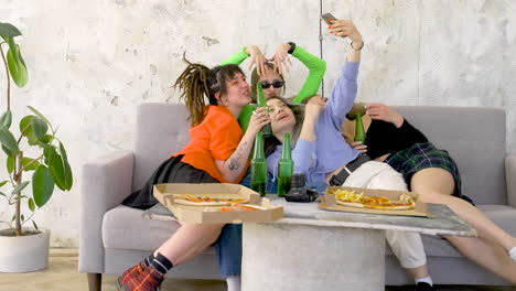 Happy-Women-Taking-Selfie-While-Holding-Beers-On-A-Sofa-At-Pizza-Party