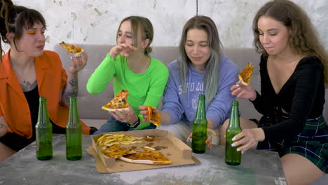 Girl-Friends-Drinking-Beer,-Eating-Pizza-And-Laughing-On-A-Sofa