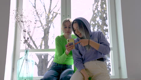 Two-Girl-Friends-Talking-While-Look-At-The-Phone
