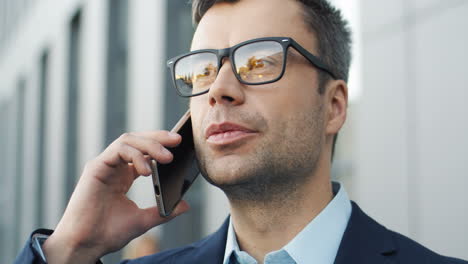 Close-Up-View-Of-Businessman-In-Glases-Talking-On-The-Phone-In-The-Street