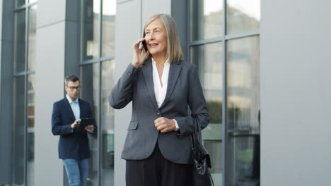 Mature-Businesswoman-Talking-On-The-Phone-In-The-Street-1