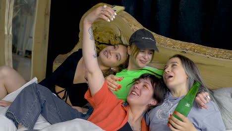 Four-Happy-Friends-Taking-Selfie-On-The-Bed