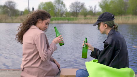Ein-Paar-Freunde-Unterhalten-Sich-Und-Trinken-Bier-Am-Flussufer