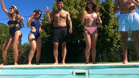 Happy-Friends-With-Cocktails-Standing-On-Edge-Of-Pool-And-Dancing