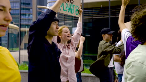 Young-Man-With-Black-Hat-Next-To-Red-Haired-Woman-With-Board-On-Protest