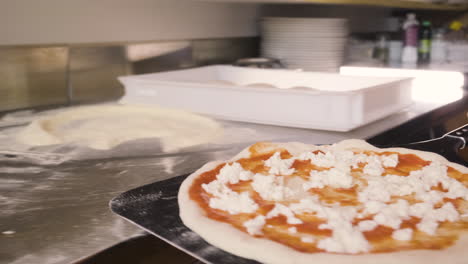 Vista-De-Cerca-De-Un-Chef-Sosteniendo-Pizza-En-Una-Bandeja-E-Insertándola-En-El-Horno-De-Piedra