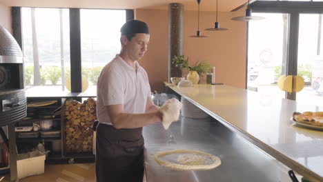 Chef-Amasando-Masa-De-Pizza-Y-Agitándola-En-El-Aire-En-La-Cocina-De-Un-Restaurante
