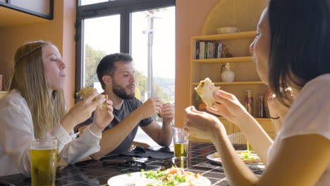 Close-Up-View-Of-Group-Of-Friends-Talking-And-Eating-Pizza-At-Restaurant-Table