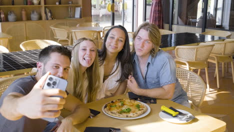 Group-Of-Friends-Taking-A-Selfie-Photo-While-Eating-Pizza-In-A-Restaurant