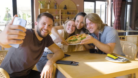 Group-Of-Friends-Taking-A-Selfie-Photo-And-Having-Fun-While-Eating-Pizza-In-A-Restaurant-1