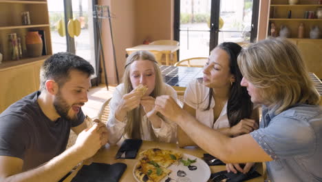 Group-Of-Four-Happy-Friends-Sharing-Pizza-And-Having-Fun-At-Restaurant-1