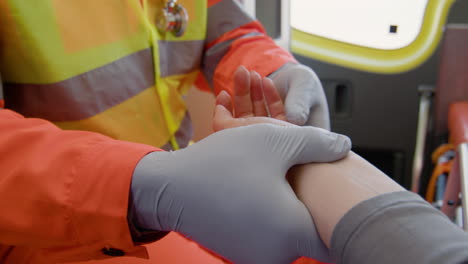 Close-Up-View-Of-A-Paramedic-Touching-The-Hand-Of-A-Patient-Lying-On-A-Stretcher-Inside-An-Ambulance