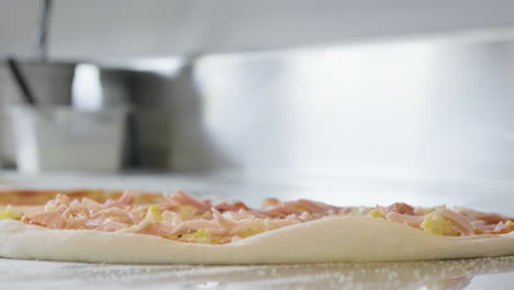 Close-Up-Of-An-Unrecognizable-Chef-Adding-Ham-On-The-Pizza-Raw-Dough-At-Restaurant