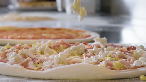 Close-Up-Of-An-Unrecognizable-Chef-Adding-Cheese-On-The-Pizza-Raw-Dough-At-Restaurant
