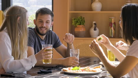Group-Of-Friends-Eating-Pizza-And-Drinking-Beer-At-Restaurant
