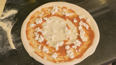 Top-View-Of-An-Unrecognizable-Chef-Adding-Cheese-On-The-Pizza-Raw-Dough