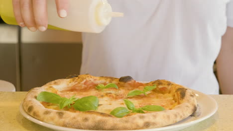 Close-Up-Of-An-Unrecognizable-Chef-Pouring-Olive-Oil-On-Baked-Margherita-Pizza