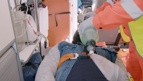 Paramédico-Masculino-Ayudando-A-Un-Paciente-Estadounidense-Herido-Usando-Equipo-Respiratorio-En-La-Ambulancia