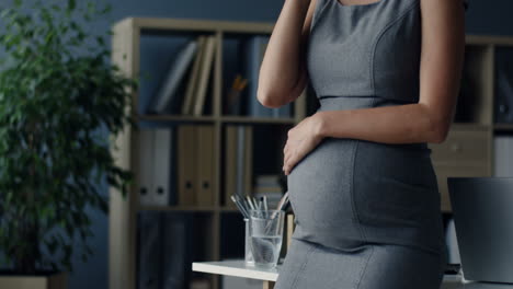 Mujer-De-Negocios-Embarazada-Hablando-Por-Teléfono-Mientras-Acaricia-Su-Vientre-En-La-Oficina