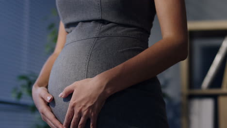Close-Up-Of-Pregnant-Businesswoman-Hands-Caressing-Her-Belly-In-The-Office
