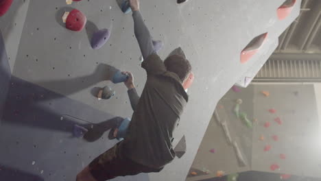 Young-Male-Athlete-Climbing-Artificial-Rock-Wall-In-Bouldering-Gym