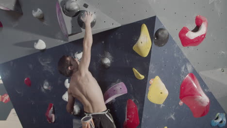 Strong-Male-Athlete-Climbing-Artificial-Rock-Wall-In-Bouldering-Gym