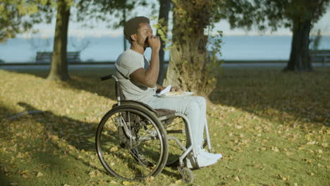 Young-Man-In-Wheelchair-Enjoying-His-Late-Lunch-In-City-Park