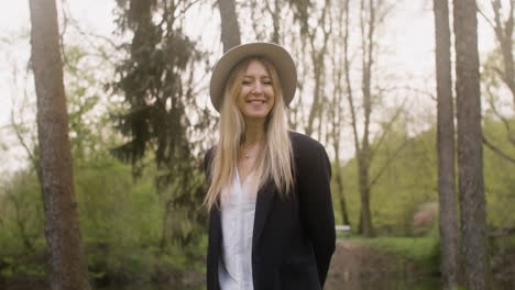 Portrait-Of-A-Happy-Blonde-Woman-With-Hat-Standing-In-The-Park-And-Looking-At-The-Camera-2