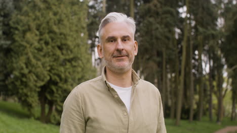 Portrait-Of-A-Gray-Haired-Man-Standing-In-The-Park-And-Looking-At-The-Camera
