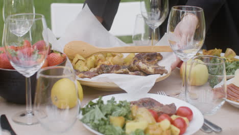 Close-Up-Of-Two-Unrecognizable-Women-Setting-Food-On-A-Dining-Table-For-An-Outdoor-Party-In-The-Park