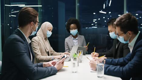 Multiethnische-Geschäftsleute-Gruppieren-Sich-In-Medizinischen-Masken-In-Einem-Teammeeting-In-Einem-Modernen-Büro-Und-Diskutieren-über-Ein-Projekt-1