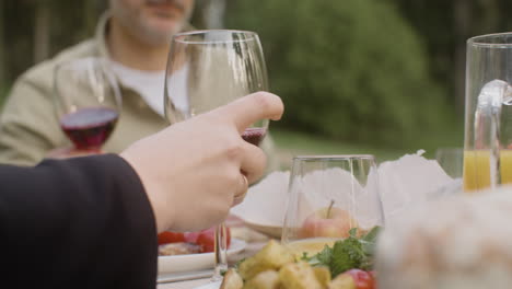 Man-Hand-Taking-Glasses-Of-Wine-From-A-Table-During-An-Outdoor-Party-In-The-Park