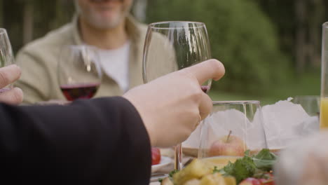 Man-Hand-Putting-A-Glass-Of-Wine-On-A-Table-During-An-Outdoor-Party-In-The-Park