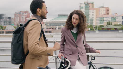 American-Man-And-Woman-Talking-To-Each-Other-While-Leaning-On-Their-Bikes-On-The-City-Bridge-1