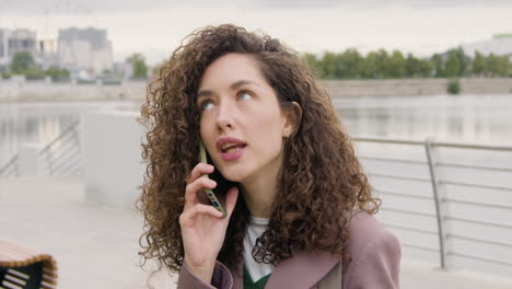 Curly-Woman-In-Formal-Clothes-And-Bicyle-Talking-On-Mobile-Phone-On-The-City-Bridge-2