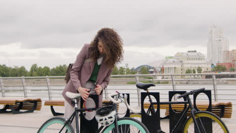 Mujer-Bonita-Con-Ropa-Formal-Estacionando-Su-Bicicleta-En-El-Puente-De-La-Ciudad-Mientras-Iba-A-Trabajar