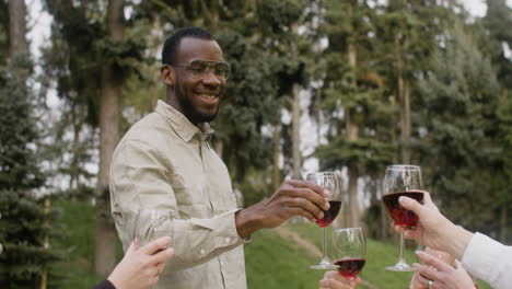 Man-Standing-In-Front-Of-A-Table-Toasting-With-His-Friends-At-An-Outdoor-Party-In-The-Park-2