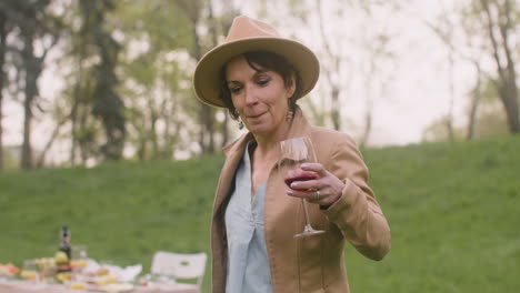 Middle-Aged-Woman-Dancing-While-Holding-A-Wine-Glass-In-The-Park